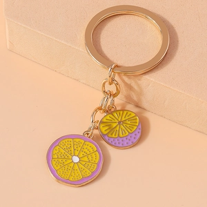 Close-up of yellow and purple enamel lemon charms on a gold keychain with chain details