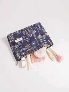 Navy blue linen makeup bag with floral embroidery and assorted cosmetics inside