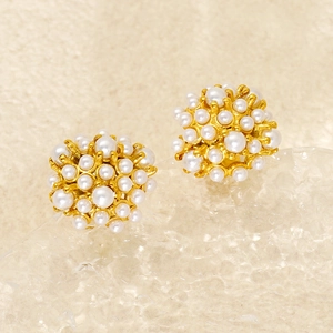 Macro shot of gold-plated cluster stud earrings featuring small white pearls in a sphere design