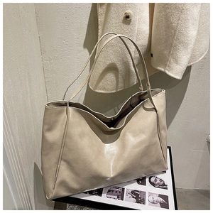 Detail of beige soft leather tote bag with magnetic closure on fashion magazine
