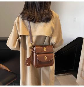 Detail of retro brown crossbody bag with double gold oval clasps and leather tag