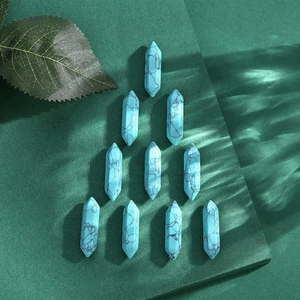 Close-up of ten hexagonal turquoise crystal pillars arranged on a green textured background