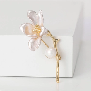 Close-up of trumpet flower brooch with pink enamel petals, gold stem, and white pearl