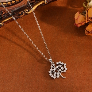 Close-up of silver Tree of Life necklace with clear stones on a vintage brown fabric background