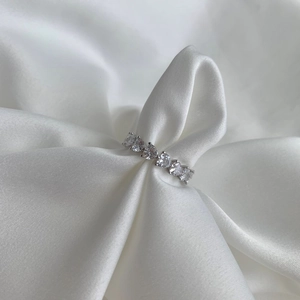 Detailed close-up of S925 sterling silver ring with heart-cut zircons on white satin