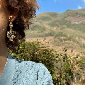 Macro detail of vintage teardrop tassel earrings with amber gemstones on a model