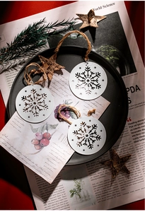 Detailed view of white metal snowflake Christmas ornaments with rustic twine on a black tray