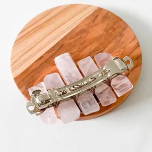 Handmade rose quartz hair clip with raw pink stones and copper wire on wood background