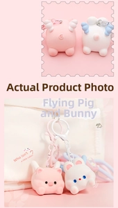 Detail of pink pig and white rabbit wing charms on white bag with metal lobster clasp
