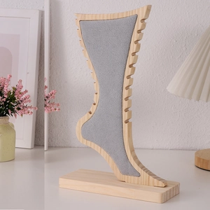 Detail of foot-shaped bamboo jewelry display stand with grey velvet and side hooks