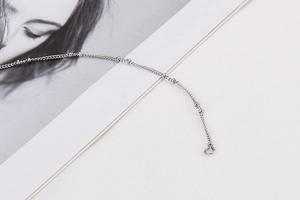 Detailed view of silver stainless steel bead chain necklace on a minimalist fashion magazine