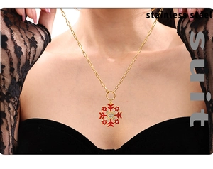 Close-up of red enamel snowflake necklace with zircons worn by a model in black dress