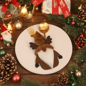 Christmas gnome cutlery holder with reindeer horns on a white plate with golden utensils