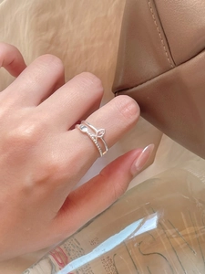 Close-up of minimalist S925 sterling silver fish line ring worn on hand with cozy backdrop