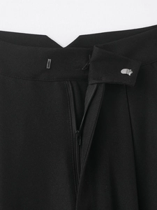 Gros plan détaillé de l'agrafe métallique et de la fermeture éclair du pantalon noir
