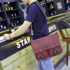 Side view of wine red canvas messenger bag on model in casual cafe setting