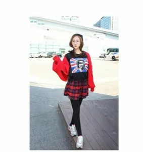 Close-up of a red knitted cardigan with detailed texture and black printed graphic t-shirt