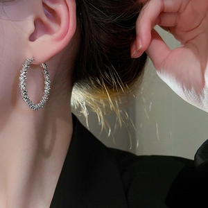 Close-up of silver hoop earrings with a textured crushed-silver finish on a model