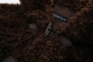 Detailed close-up of dark brown faux fur coat showing soft texture and black toggle closure