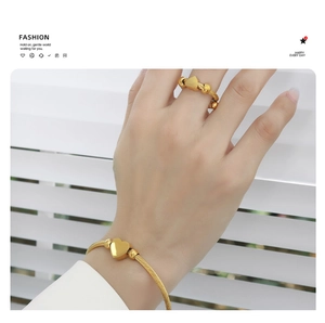 Close-up of golden cable-style heart ring and bracelet jewelry set on hand