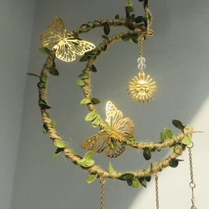 Macro shot of sun and moon dream catcher featuring artificial leaves and golden butterflies