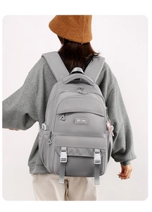 Close-up of minimalist grey nylon backpack featuring a brand logo and multi-pocket structure