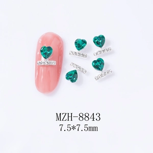 Detail of emerald green heart nail charms with silver base measuring 7.5x7.5mm