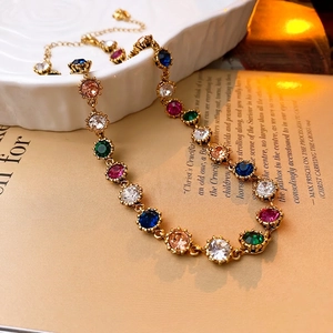 Vintage Baroque style gold necklace featuring multi-color gemstones on a ceramic plate
