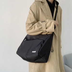 Detail of black nylon messenger bag worn by model showing large capacity and texture