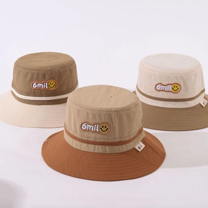 Close-up of color-block bucket hats featuring smiley face embroidery and nylon fabric texture