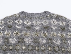 Close-up of gray knit sweater featuring white floral jacquard and ribbed crew neck