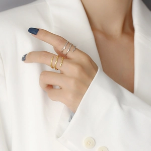 Detail shot of stacked textured rings in gold and silver finish on a model's hand