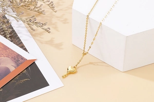 Detail shot of a golden heart key pendant on a chain over a minimalist aesthetic background