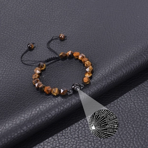 Macro detail of faceted tiger eye stone beads and 100 languages projection bead on bracelet