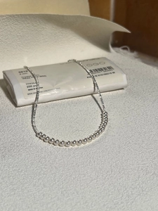 Detailed macro view of an S925 silver chain with 8mm white pearls on a textured surface