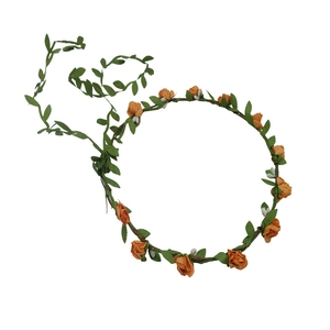 Detailed view of orange fabric flowers and green vine leaves on a floral bridal headband