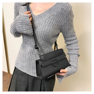 Detail shot of black stone-patterned crossbody bag with elegant matte metal shield buckle