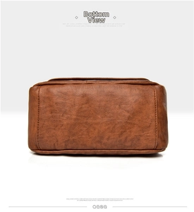 Detail view of the brown leather handbag base showing reinforced stitching and fine texture