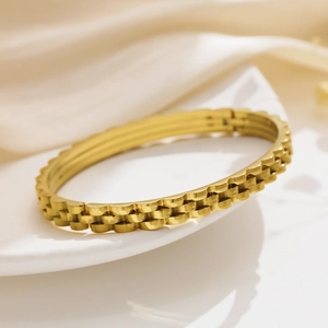 Macro side view of gold stainless steel triple-layer gear style strap bracelet