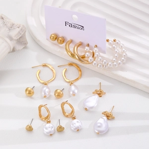 Set elegante di orecchini a cerchio dorati con perle barocche su vassoio strutturato