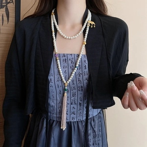 Detail of multi-layer pearl body chain with pink tassel and gold lotus accents