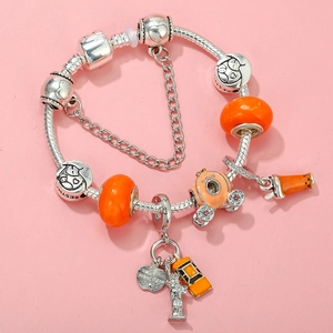 Detail view of silver snake chain bracelet featuring orange glass beads and city charms