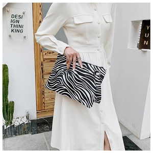 Detail of zebra pattern clutch with large silver metal ring zipper held by a model