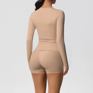 Rear view of a tight long-sleeve yoga set with high-waist shorts in soft nude tones