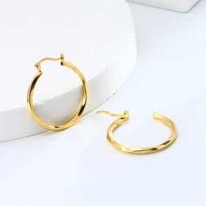 Detailed view of 925 sterling silver golden twisted hoop earrings on white stones