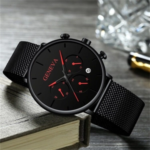 Detail of Geneva men's watch dial with red hands on black mesh band over books