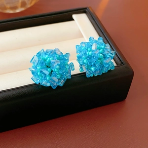 Detail of blue beaded cluster earrings featuring faceted beads on white jewelry box
