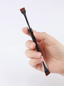 Close-up of double-ended angled eyebrow and eyeliner brush with dense synthetic bristles