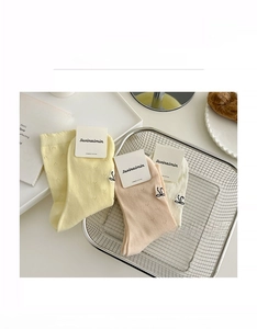 Three pairs of soft combed cotton crew socks in pastel cream colors with embroidery detail