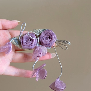 Detail of purple satin floral earrings with flowing tassel petals and silver leaves
